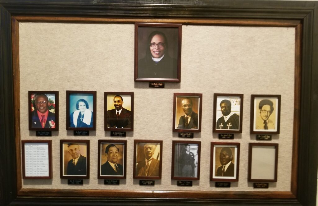 Wall of photos from Clair Memorial United Methodist Church's history of pastors.
